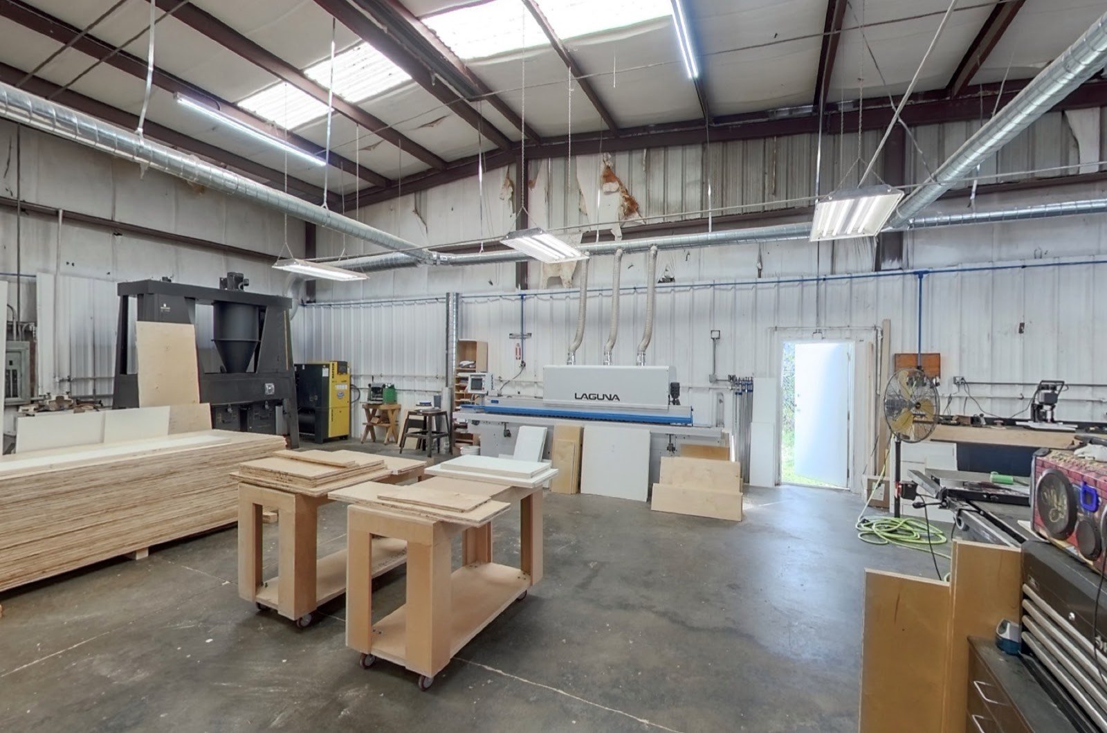 Shop floor at Coastal Precision CNC — Laguna CNC router and material staging